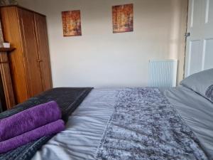 a bedroom with a bed with purple pillows on it at Shergold Rooms in Swindon