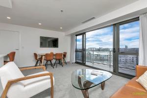 a living room with a couch and a glass table at QV Stays Upscale Modern Getaway in Auckland