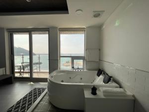 a bathroom with a large tub and a large window at Somewhales Pension in Namhae
