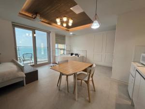 cocina y sala de estar con mesa y sillas en Somewhales Pension, en Namhae