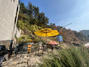 a patio with a table and chairs and an umbrella at Somewhales Pension in Namhae