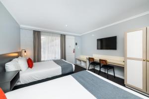 a hotel room with a bed and a desk at River Motel in Queanbeyan