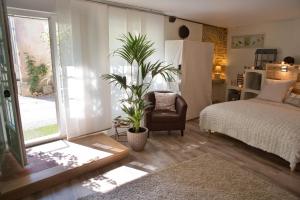 a bedroom with a bed and a chair and a window at Le Clos de la Chouette in Pommard