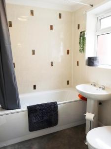 La salle de bains est pourvue d'une baignoire blanche et d'un lavabo. dans l'établissement Logan House, Modern and Spacious Townhouse close to City Centre, à Carlisle