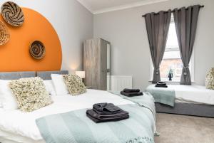 a bedroom with two beds and an orange wall at Logan House, Modern and Spacious Townhouse close to City Centre in Carlisle