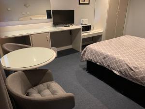 a hotel room with a bed and a desk and chairs at Casey on Princes Motel in Hallam