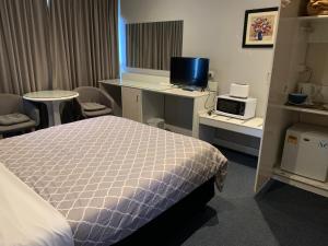 a room with a bed and a desk with a computer at Casey on Princes Motel in Hallam