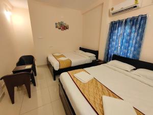 a hotel room with two beds and a chair at La Township Residency in Puducherry