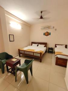 a bedroom with two beds and a table and chairs at La Township Residency in Puducherry