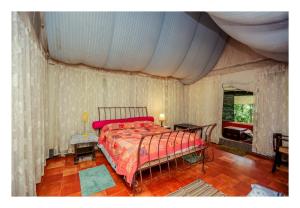 a bedroom with a bed with a red comforter at Grassroots Wayanad, Valley-view Tents in Vythiri