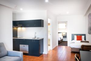 a kitchen with a sink and a living room with a bed at River Motel in Queanbeyan