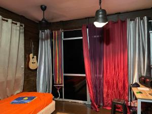 a bedroom with a bed and a window with a guitar at Hj Hassan Floating Cabin in Kuala Terengganu