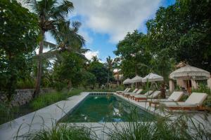 a swimming pool with lounge chairs and umbrellas at Diamond Beach Villas in Nusa Penida