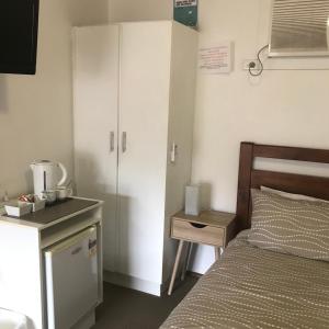 a bedroom with a bed and a cabinet and a table at Mt. Remarkable Hotel Motel in Melrose