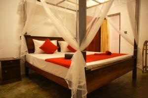 a bedroom with a canopy bed with red pillows at Coastal House in Mirissa