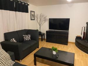 uma sala de estar com um sofá e uma televisão de ecrã plano em Quetzal House em Tijuana