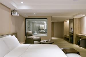 um quarto de hotel com uma cama e uma cadeira em Spring Rhapsody Hotel em Taichung