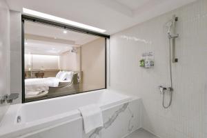 a bathroom with a mirror and a tub and a bed at Spring Rhapsody Hotel in Taichung