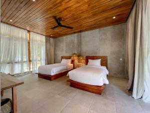a bedroom with two beds and a wooden ceiling at Diamond Beach Villas in Nusa Penida