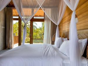a bedroom with a large bed with white pillows at Diamond Beach Villas in Nusa Penida