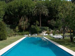 a swimming pool in a yard with chairs and trees at Hotel Sintra Jardim in Sintra