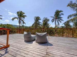 two chairs sitting on a wooden deck with palm trees at Diamond Beach Villas in Nusa Penida