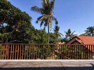 a wooden fence in front of a house with a palm tree at Diamond Beach Villas in Nusa Penida