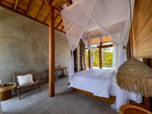 um quarto com uma cama de dossel e uma cadeira em Diamond Beach Villas em Nusa Penida