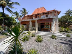a house with a wooden roof and palm trees at Diamond Beach Villas in Nusa Penida