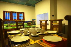 einem Holztisch mit weißen Tellern und Tassen darauf in der Unterkunft Coastal House in Mirissa