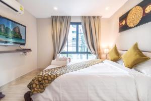 een slaapkamer met een groot wit bed en een televisie bij Citismart Luxury Apartments in Pattaya