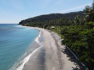 an empty beach with palm trees and the ocean at Living Asia Resort and Spa in Senggigi