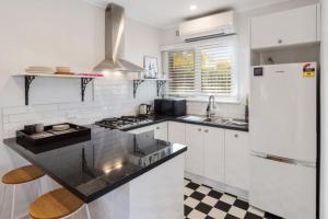 a kitchen with white appliances and a black counter top at On The Beach in Rosebud