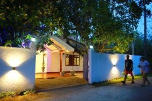 dwoje ludzi przechodzi przez białą ścianę w nocy w obiekcie Coastal House w mieście Mirissa