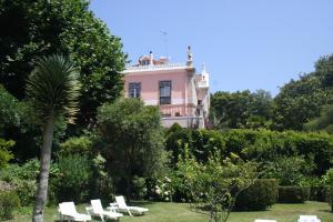 a pink house with a palm tree and white chairs at Hotel Sintra Jardim in Sintra