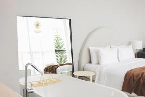 a white hotel room with a bed and a window at Sundance Dayclub Hua Hin in Hua Hin