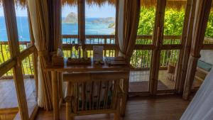 a room with a table with a view of the ocean at Elang Hillside Bamboo Villas in Labuan Bajo
