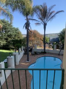 ロードポートにあるSafari Deluxe Rooms - elegant rooms with access to beautiful garden & poolのヤシの木が植わるバルコニーからスイミングプールの景色を望めます。