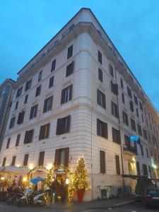 un bâtiment avec un arbre de Noël devant lui dans l'établissement Hotel Touring, à Rome