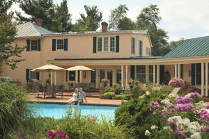 two people sitting by a pool in front of a house at L'Auberge Provencale Inn & Restaurant in Boyce