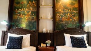 a bedroom with two beds and a painting on the wall at Cheva Gallery Boutique Hotel in Chiang Mai