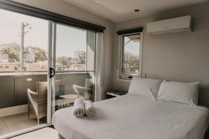 1 dormitorio con cama blanca y balcón en Saltwater Villas - Pet Friendly Accommodation en Mooloolaba
