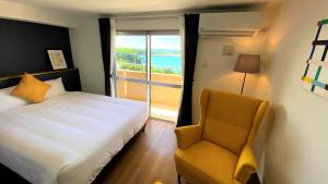 ein Schlafzimmer mit einem Bett, einem Stuhl und einem Fenster in der Unterkunft Hotel Miyakojima in Miyako-jima