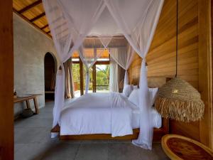 a bedroom with a white bed with a canopy at Diamond Beach Villas in Nusa Penida