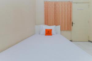 Una cama blanca con una almohada naranja. en Koolkost @ Siwalankerto en Surabaya