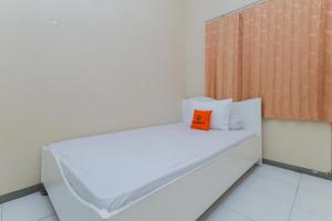 Cama blanca con almohada naranja en una habitación en Koolkost @ Siwalankerto en Surabaya