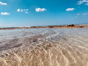 una spiaggia sabbiosa con onde in acqua di Verde Blu Vacanze Suites a Porto Cesareo