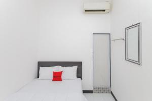 1 dormitorio con cama blanca y almohada roja en RedDoorz near Mayapada Hospital Surabaya, en Surabaya
