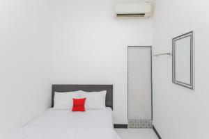a bedroom with a white bed with a red pillow at RedDoorz near Mayapada Hospital Surabaya in Surabaya