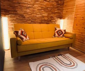 ein gelbes Sofa in einem Zimmer mit Ziegelwand in der Unterkunft MoodySun Studio, remote tiny home in Comarnic